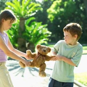 2 kids tugging on a teddy bear