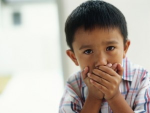 little boy covering his mouth