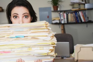 Woman behind a large pile of papers